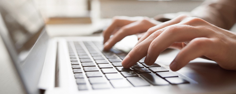hands typing on macbook keyboard